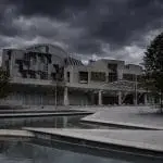 The Holyrood building overshadowed by a grey dark overcast sky