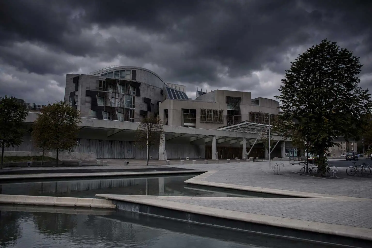 The Holyrood building overshadowed by a grey dark overcast sky