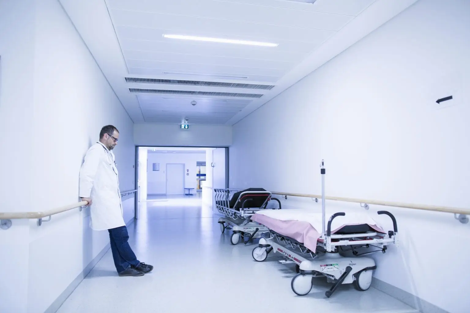 Worried doctor with head down in hospital corridor