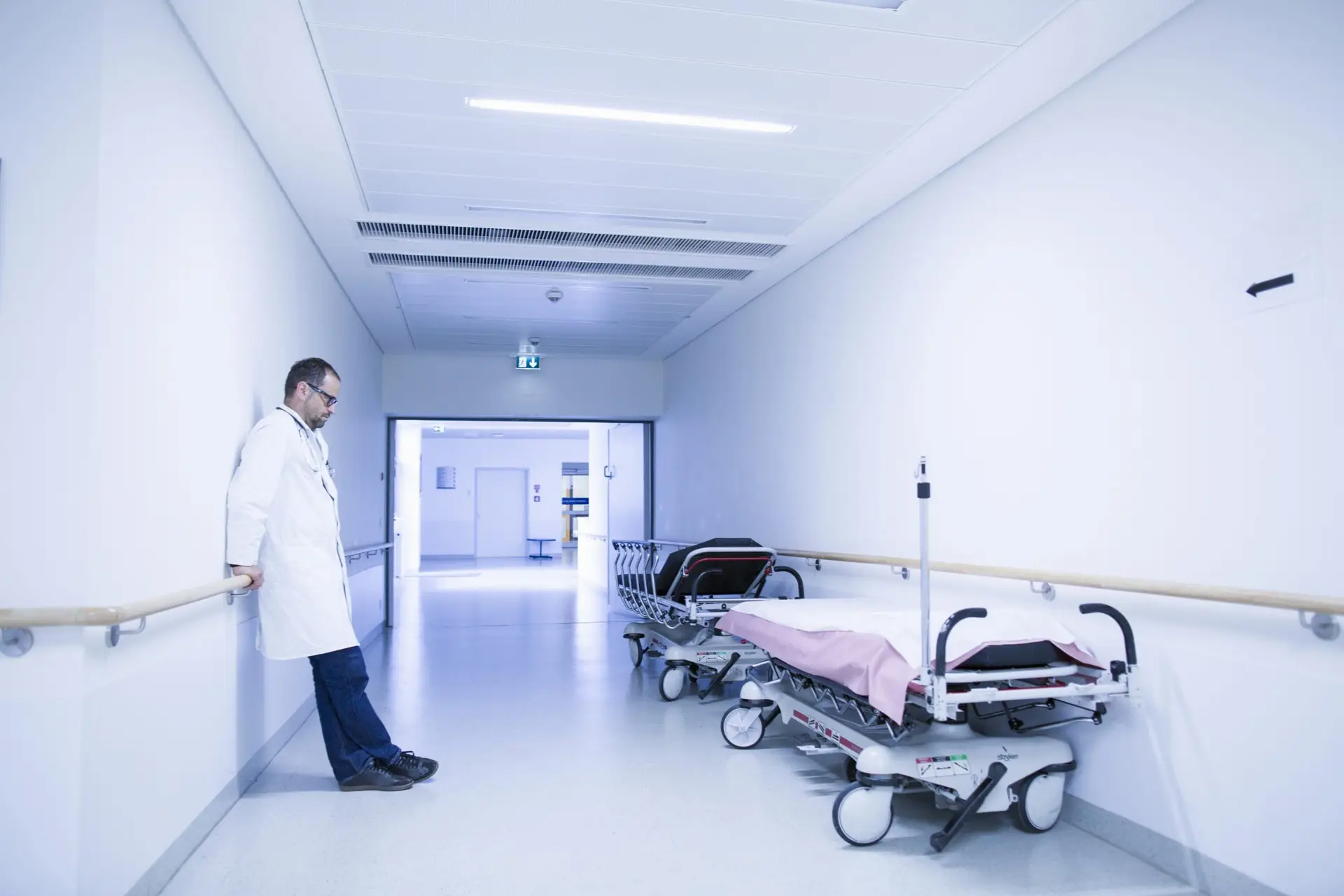 Worried doctor with head down in hospital corridor