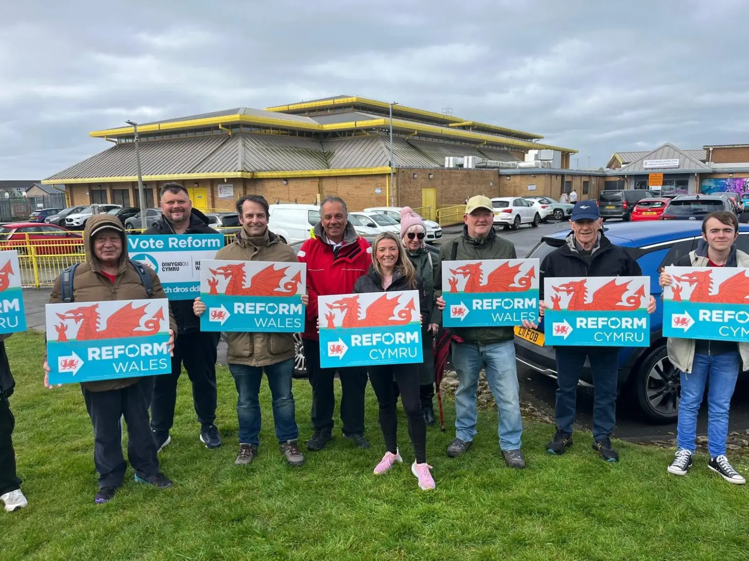 Campaigners holding placards for Reform UK Wales/CYMRU